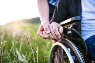 Two individuals outdoors, one in a wheelchair, symbolizing support and companionship, underlining the importance of disability benefits.