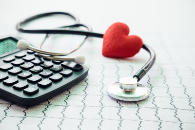 Calculator and stethoscope on EKG graph paper with a red heart, symbolizing federal medical insurance.