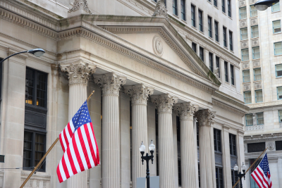 Two American flags flanking the entrance of a neoclassical government building with Corinthian columns, representing federal employment and disability services.