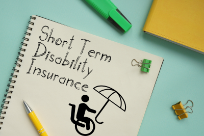 A notebook with the words “Short Term Disability Insurance” written on it, an umbrella symbol, and a wheelchair symbol, indicating coverage for disabilities.