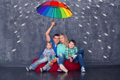 Family sitting under a colorful umbrella, symbolizing FERS survivor benefit protection.