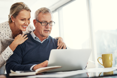 Couple reviewing federal retirement planning on a laptop, looking confident and optimistic.