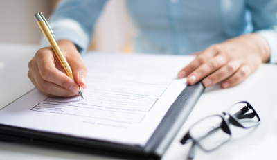 Filling out US government disability benefits form with pen and clipboard.