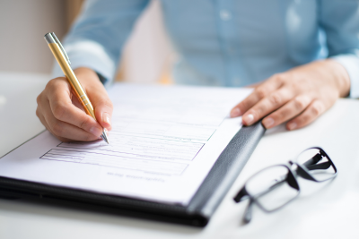 Filling out US government disability benefits form with pen and clipboard.