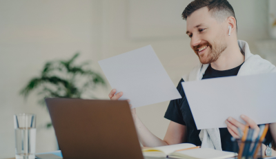 Smiling man reviewing documents at a laptop, representing federal employee disability benefits.