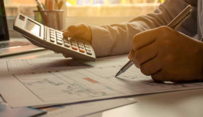 A person calculating finances with a calculator and documents related to federal employee disability pay.