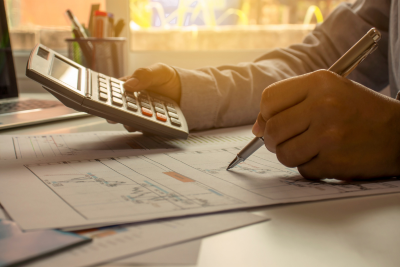 A person calculating finances with a calculator and documents related to federal employee disability pay.