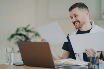 Smiling man reviewing documents at a laptop, representing federal employee disability benefits.